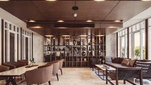 Un interior moderno con comedor, asientos y una gran estantería llena de objetos decorativos.