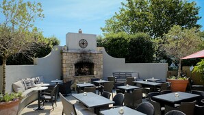 An outdoor patio with stone fireplace, wicker furniture, and potted plants. - The Horse & Hound (Delgany)