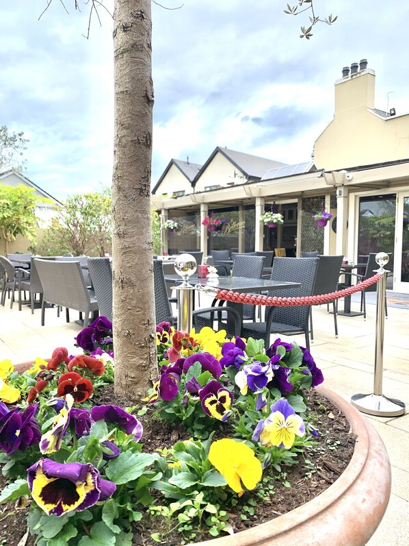 An outdoor seating area with wicker chairs and a potted flower arrangement.