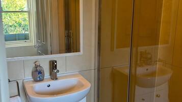 A bathroom with a white sink, a mirror, and a glass-enclosed shower area.