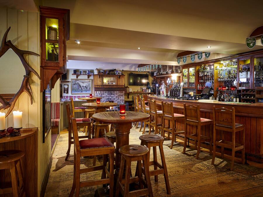 Un espace bar avec des meubles en bois, une grande décoration en forme de bois de cerf et une variété de bouteilles et de verres exposés sur des étagères.