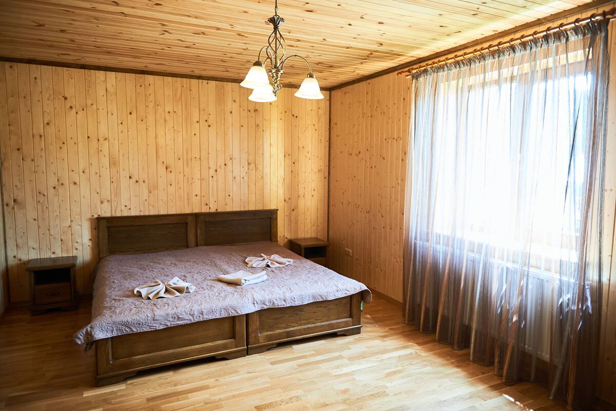 Un dormitorio con paneles de madera, una cama, mesitas de noche y un candelabro.
