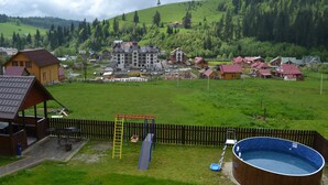 Ein Wohngebiet mit einem großen Holzhaus, einem Schwimmbad und einem Spielplatz.