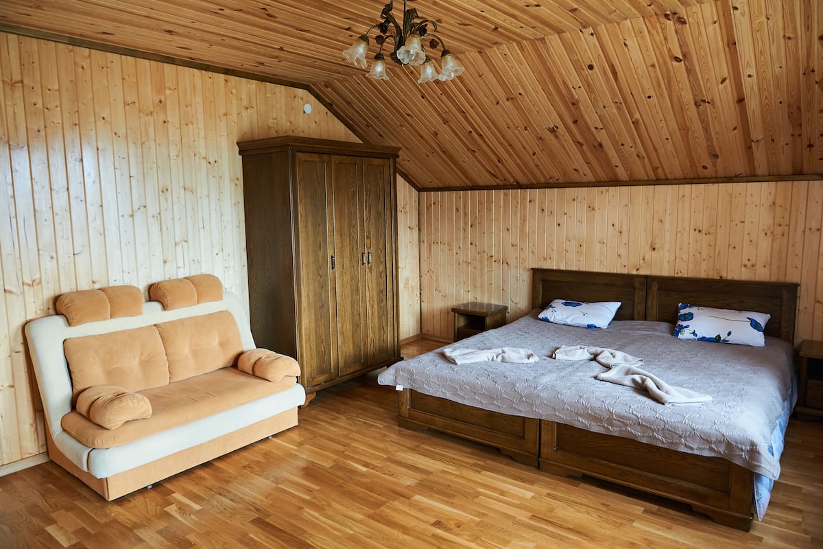 Una habitación con paneles de madera, una cama, un sofá y un armario.