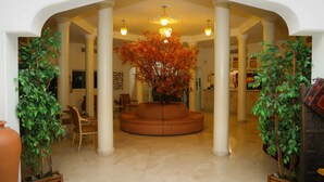 Un vestíbulo con una zona de estar central, columnas y un gran árbol con hojas otoñales.