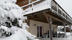 Una cabaña de madera con porche cubierto y árboles cubiertos de nieve.