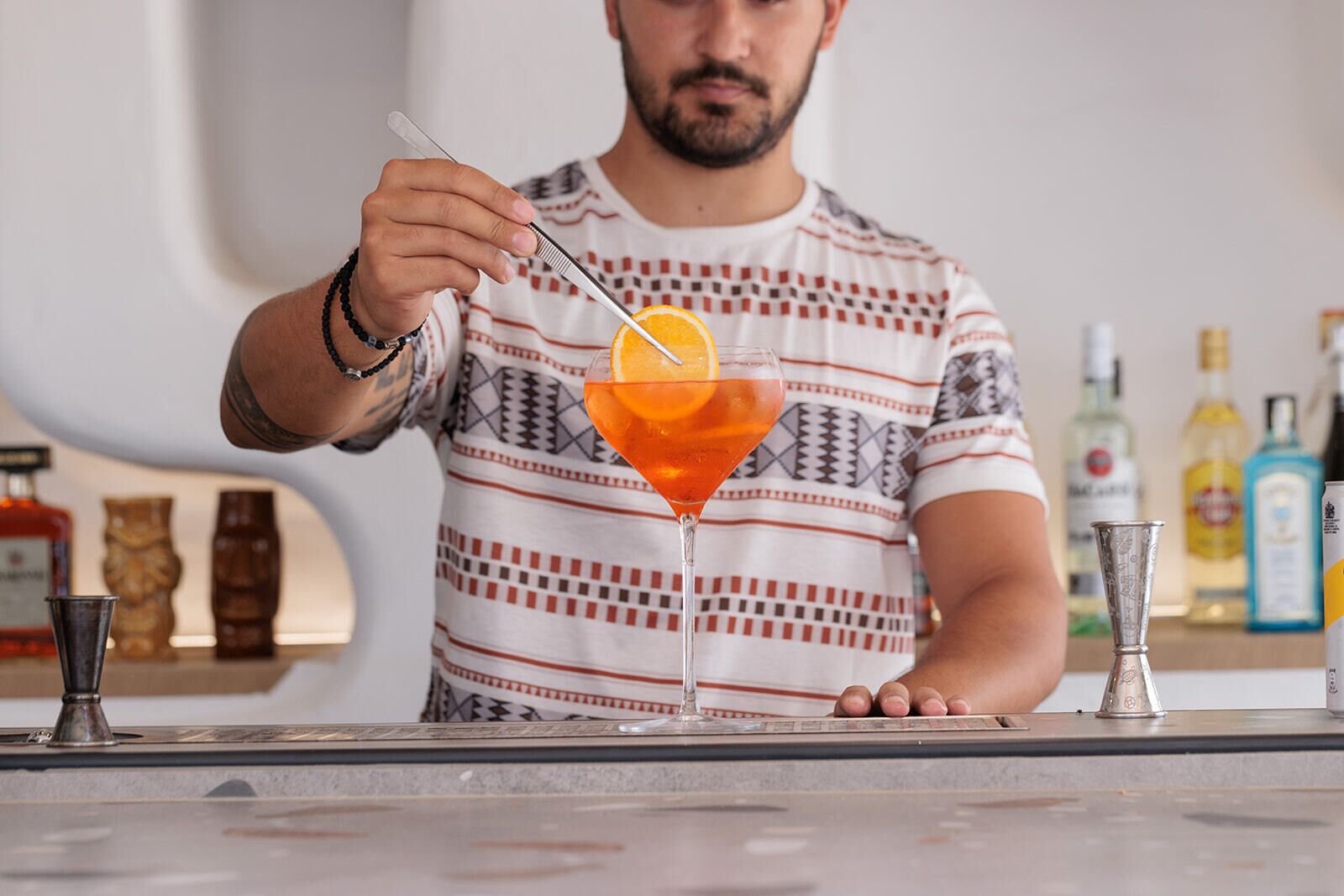 Un barman tenant un shaker à cocktails avec une tranche d’orange.