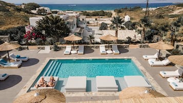 Alberca al aire libre, sombrillas en la alberca y camastros