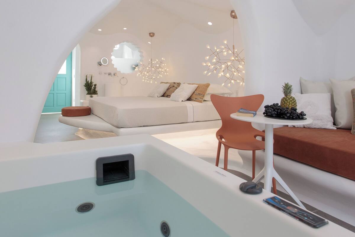 A modern interior with a white curved wall, a seating area with a table, and a small pool.