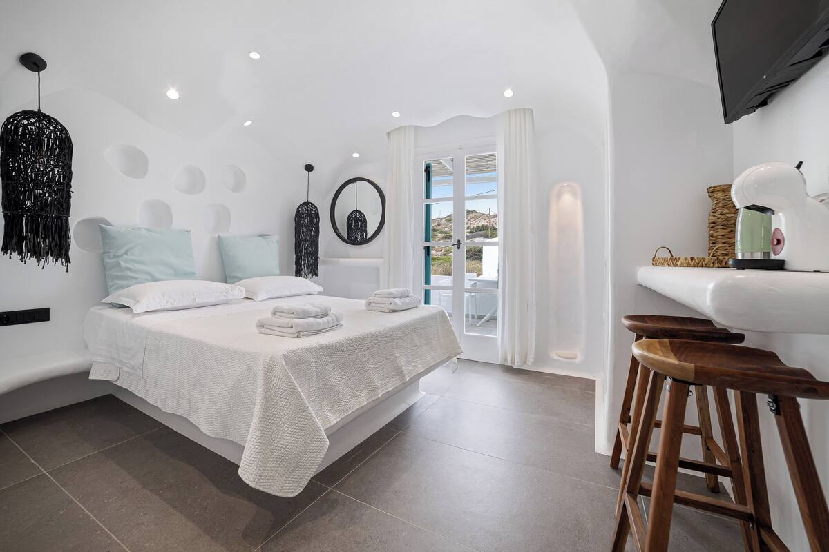 A modern bedroom with a bed, a sink, and a bar stool.