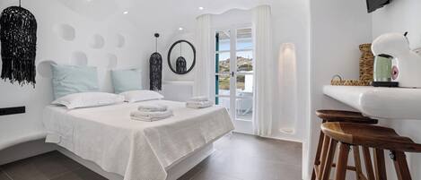 A modern bedroom with a bed, a sink, and a bar stool.