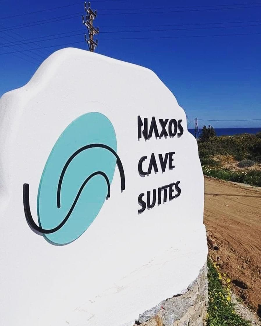 Un letrero para Naxos Cave Suites con un logotipo estilizado.