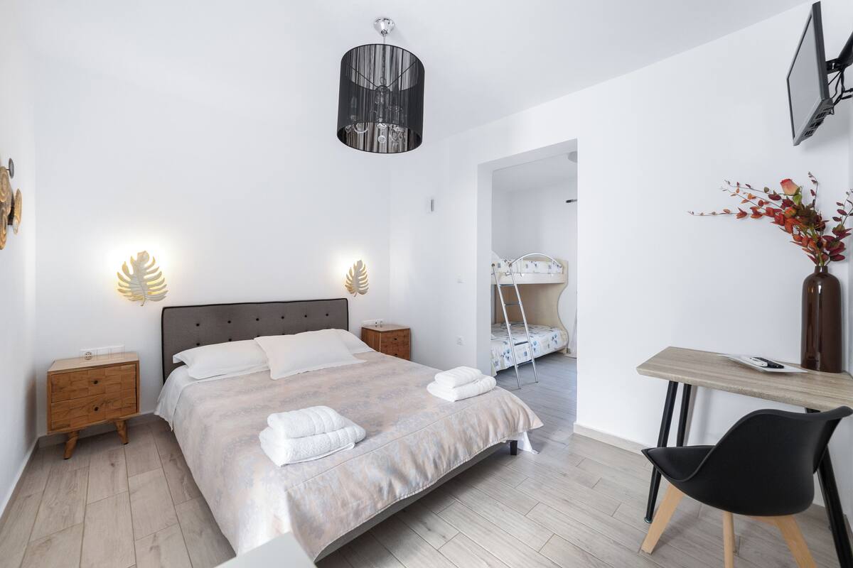 A modern bedroom with a large bed, bedside tables, a desk, and a chair.
