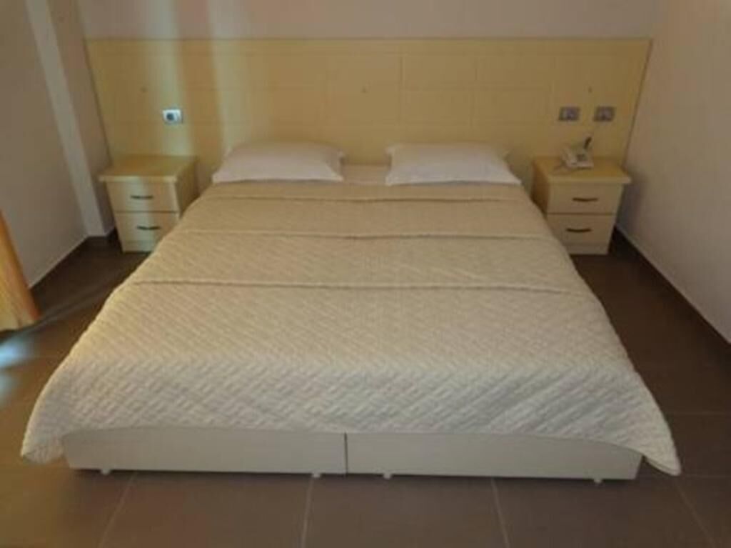 A standard hotel room with a single bed, two bedside tables, and a headboard.