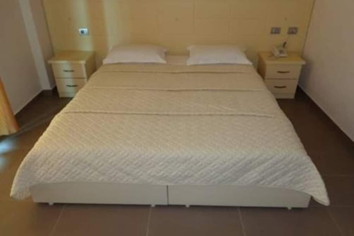 A standard hotel room with a single bed, two bedside tables, and a headboard.