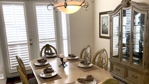 A dining room with a large oval table, ornate chairs, a chandelier, and a classic cabinet with glass doors. - Dolphin's Retreat Near Disney (Kissimmee)