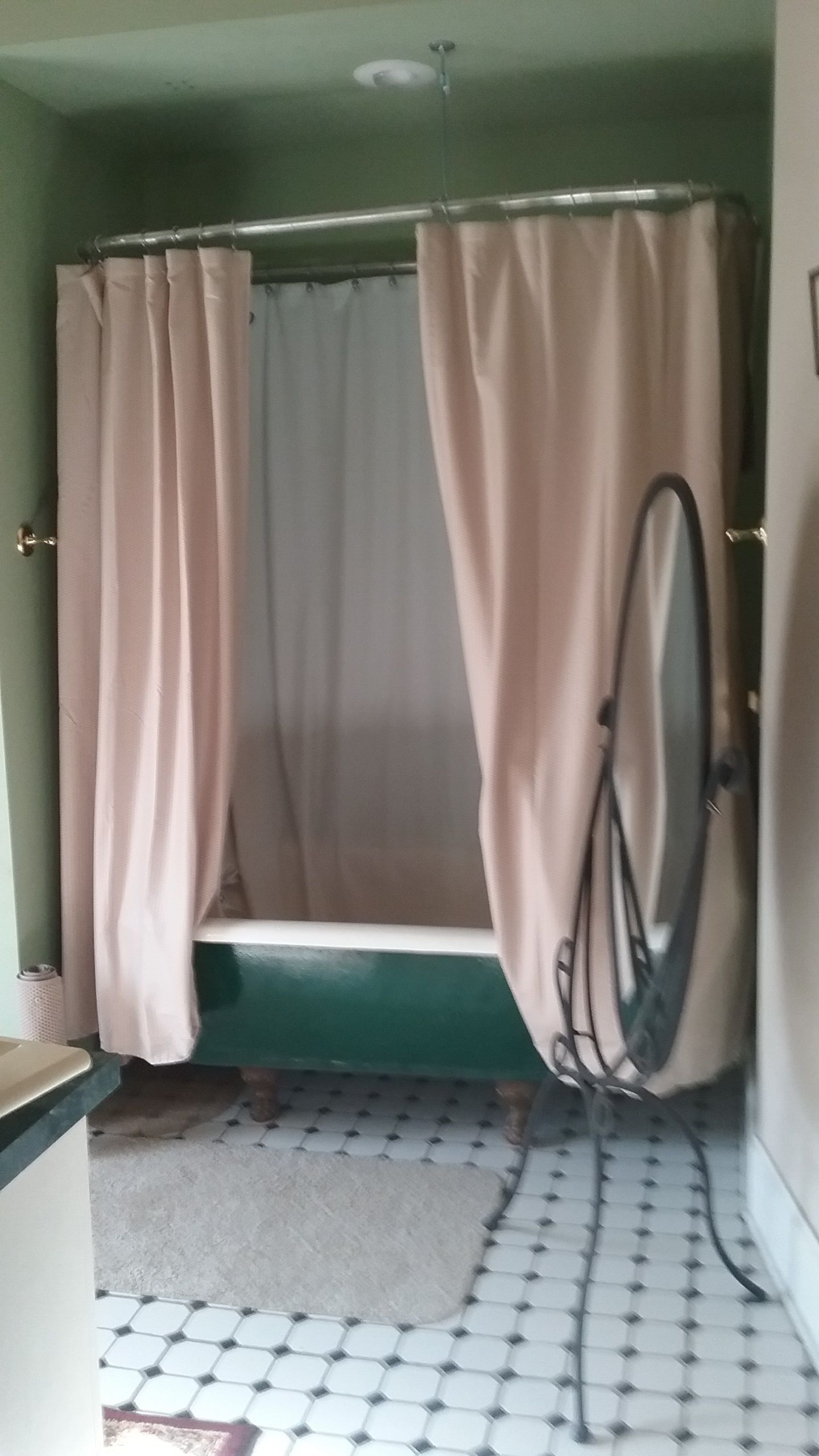 Ein Badezimmer mit Duschbereich, einer grünen Bank, einem weißen Waschbecken und einem gemusterten Boden.
