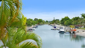 A marina with boats docked along a calm waterway, surrounded by lush greenery and palm trees.