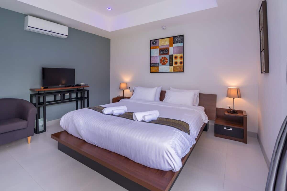 Quarto de hotel moderno com uma cama grande, abajures, televisão de tela plana e ar condicionado fixado na parede.