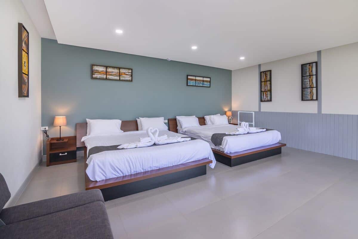 Quarto de hotel com duas camas, um sofá e obras de arte nas paredes.