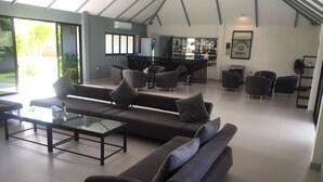 A modern living area with a large sofa set, a coffee table, and a bar area with shelves of bottles. - Tamara Resort Bangsary (Sattahip)