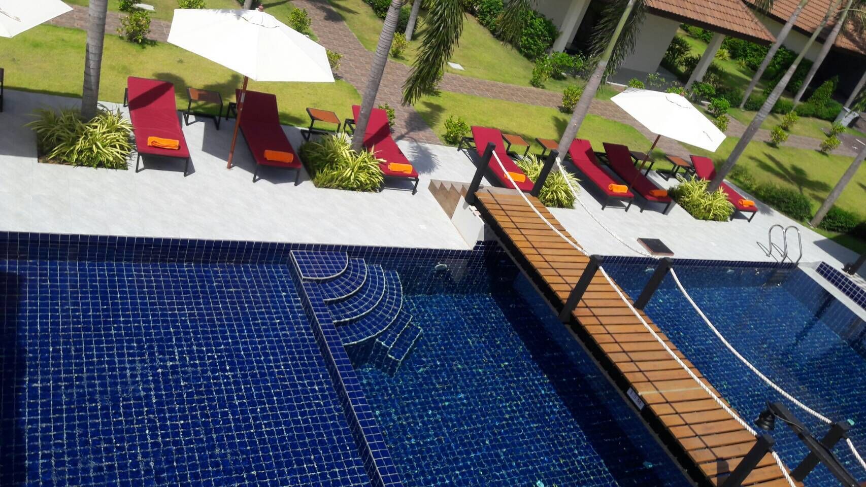 A swimming pool with a tiled deck and sun loungers.