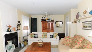 A living room with a fireplace, a white sofa, a green coffee table, and a floral sofa. - Charming 4BR TH – Steps to Downtown & Boardwalk Fun–Bethany Winds, Bethany Beach (Bethany Beach)