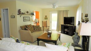 A living room with a sofa, a coffee table, a television, and a ceiling fan. - Charming 4BR TH – Steps to Downtown & Boardwalk Fun–Bethany Winds, Bethany Beach (Bethany Beach)