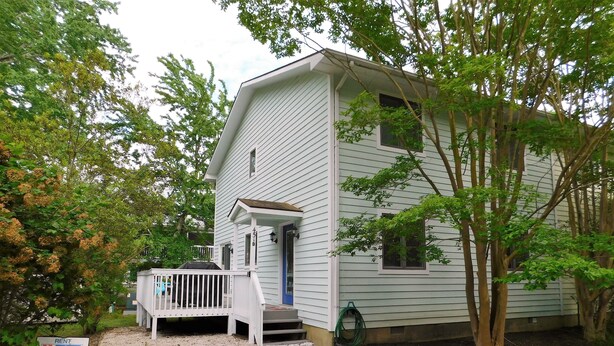A two-story house with a porch, a covered entryway, and a gravel driveway. - Charming 4BR TH – Steps to Downtown & Boardwalk Fun–Bethany Winds, Bethany Beach (Bethany Beach)