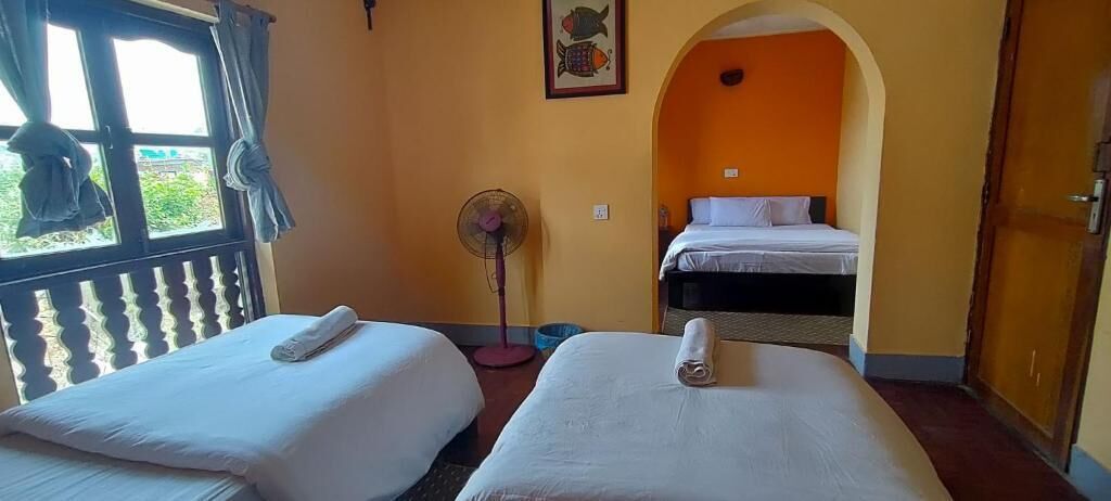 Una habitación con dos camas, un ventilador y una ventana con cortinas.