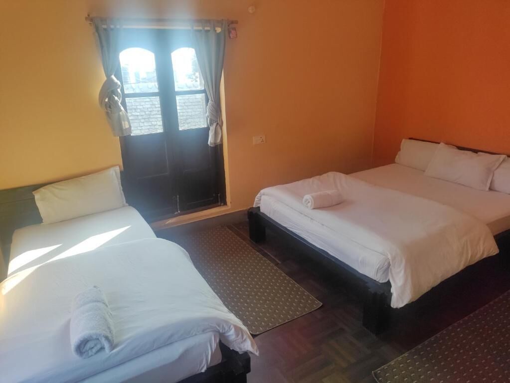 A room with two beds, a window with curtains, and a door.