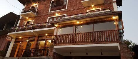 A multi-story building with balconies, large windows, and a brick facade.