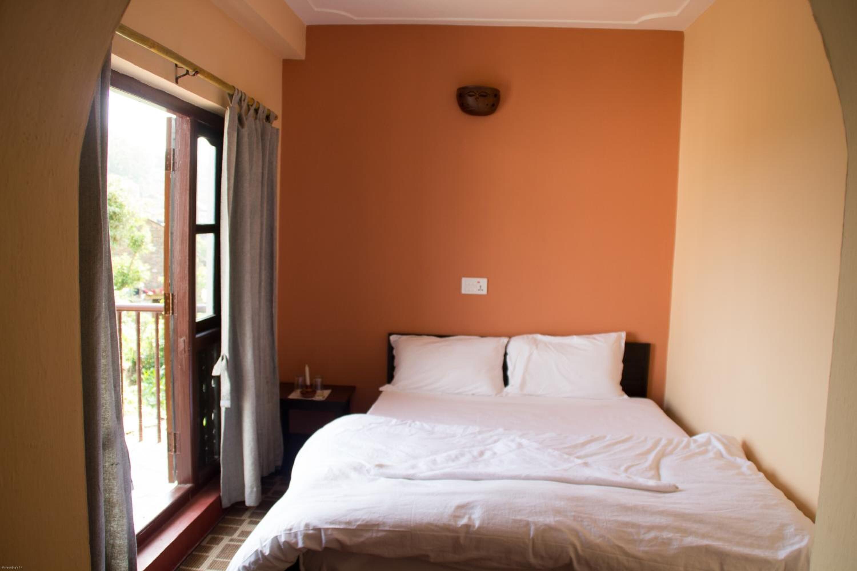 A bedroom with a bed, a nightstand, and a window with curtains.