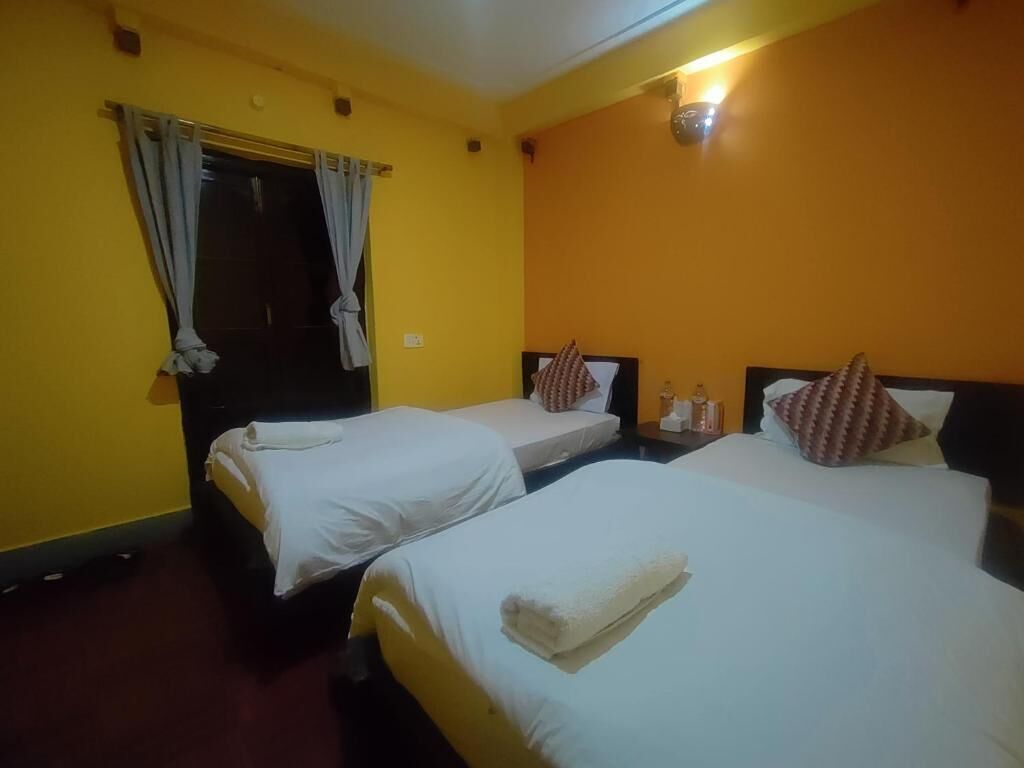 A hotel room with two beds, a door, and a wall-mounted light fixture.