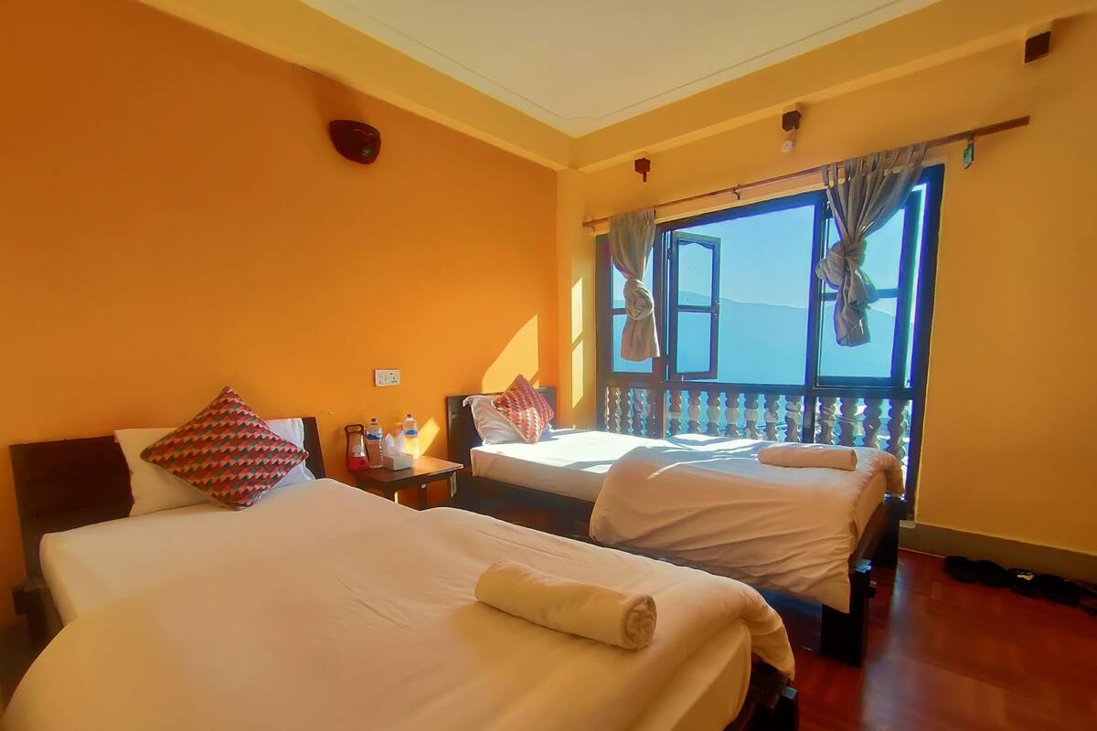 A hotel room with two beds, a window with a view, and a wooden floor.