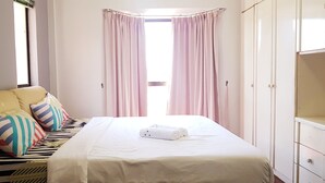A bedroom with a bed, pillows, a wardrobe, and a window with curtains. - KK City HomeSuite at KK City Center 1 (Kota Kinabalu)