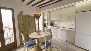 A kitchen with white cabinets, a white refrigerator, a microwave, and a sink. There is a round table with blue chairs and a hanging light fixture. - SUITE APARTMENT - 1 HABITACIÓN VISTAS A CALLE (Villajoyosa)