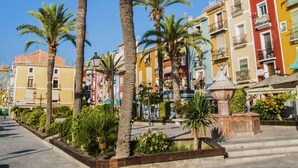 A street with palm trees and colorful buildings. - SUITE APARTMENT - 1 HABITACIÓN VISTAS A CALLE (Villajoyosa)