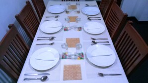 Mesa de comedor preparada para seis personas, con platos blancos, cubiertos y cristalería.