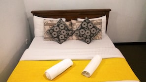 A bed with a wooden headboard, two patterned pillows, and a yellow bedspread.