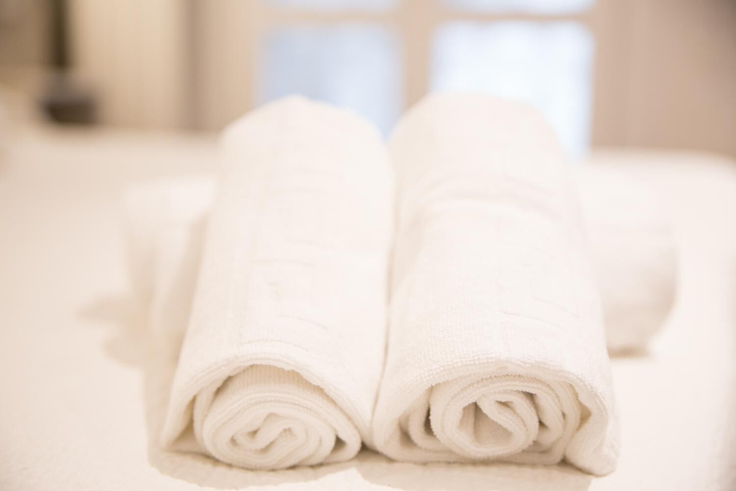 Two rolled white towels on a bed.