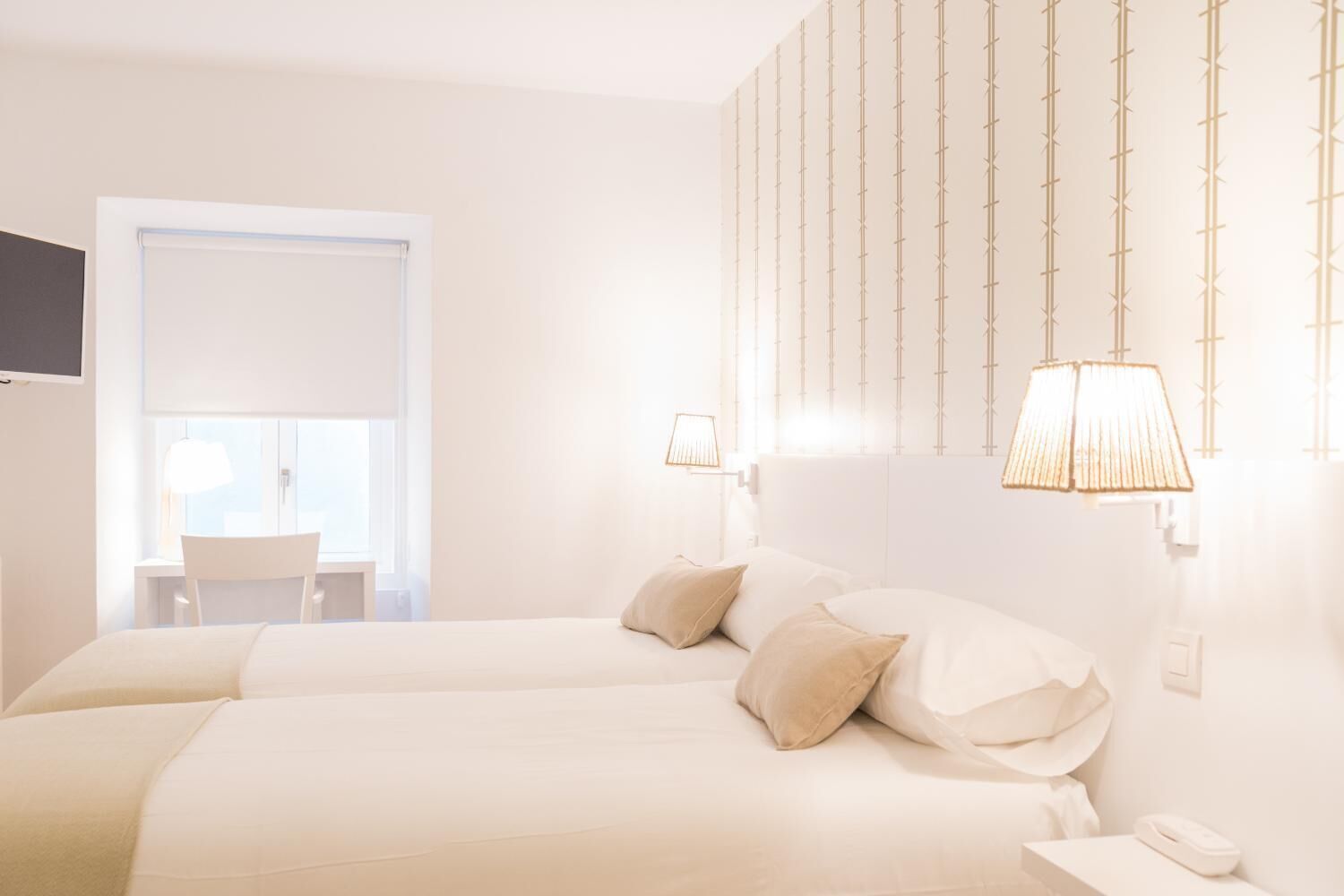 A hotel room with two beds, a desk, and a chair.
