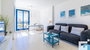 A modern living room with a sofa, a dining table, and a view of the city through a large window. - Estrella de Calpe 8C - Grupo Turis - Calpe, Costa Blanca (Calpe)