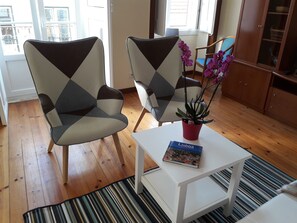 Un salon avec deux fauteuils, une table basse sur laquelle repose un livre, une plante en pot et un meuble en bois.