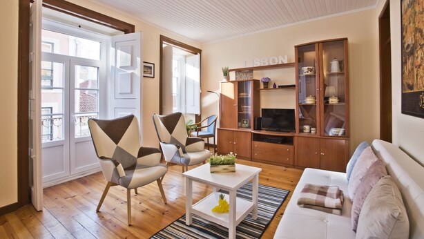A living room with a sofa, two armchairs, a coffee table, and a cabinet with a television.