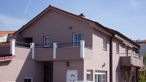 A two-story building with a balcony, a door, and windows.