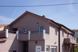 A two-story building with a balcony, a door, and windows.