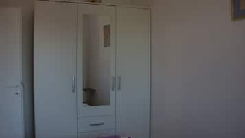 A bedroom with a bed, a wardrobe, and a mirror.