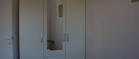 Une chambre à coucher avec un lit, une armoire et un miroir.