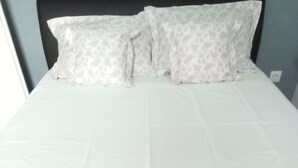 A neatly made bed with white linens and two red towels folded at the foot.